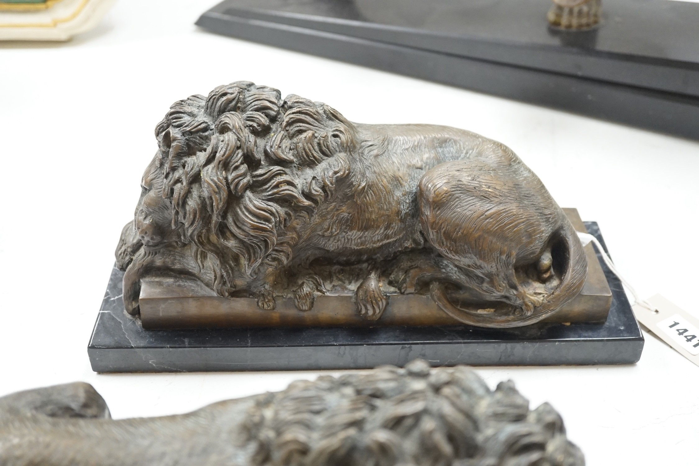 A pair of bronze recumbent lions on black marble bases 33cm